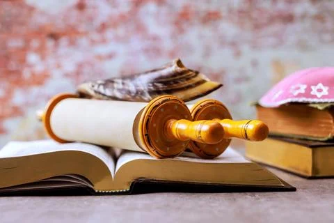 Religious torah scroll on open Holy book beside traditional items during Jewish Stock Photos