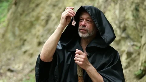 Religious wanderer carefully examines an ancient amulet during a spiritual quest Stock Footage 336785067