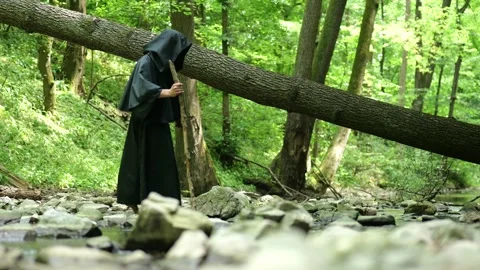 Religious wanderer explores a natural area near water while continuing a pilgrim Stock Footage 336695600