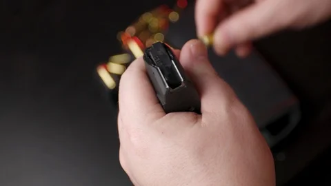 Reloading 9mm magazine bullets in background Stock Footage 124188766