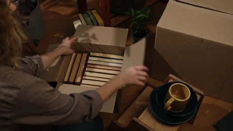 Relocation, movement concept. Young woman unpacking moving boxes. Video stock 256872161