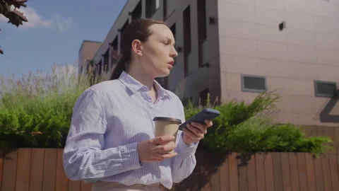Reluctantly Answering Call While Holding Coffee Near Office Building Stock Footage 306578260
