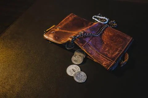 Remaining coins spilled from a worn empty wallet Foto stock