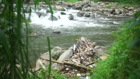 The remaining rubbish that was stranded on river rocks Stock Footage 300323236