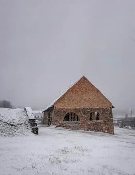 Remains of an old barn made of bricks in the falling snow. Foto stock