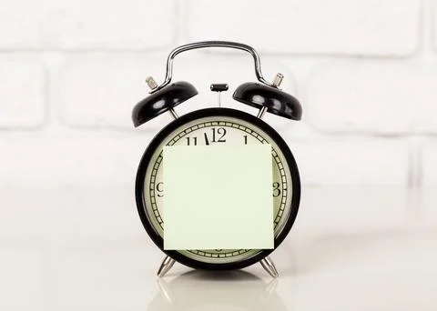 Reminder note and black old-fashioned alarm clock Stockfoto's