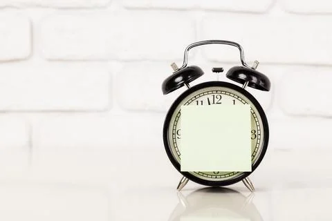 Reminder note and black old-fashioned alarm clock Stockfoto's