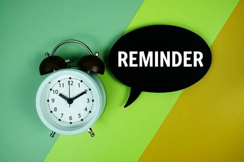 Reminder text on speech bubble with alarm clock top view on green and yello.. Stock Photos