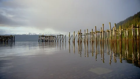 Remnants of an abandoned dock with snowy mountains in the background Stock Footage 113261835
