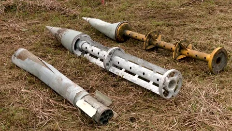 Remnants of exploded cluster munitions on the grass. Russian army shells Stock Footage 221512578