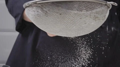 The remnants of flour in a sieve fall on the table. Leftover ingredients for the 스톡 동영상 156666934