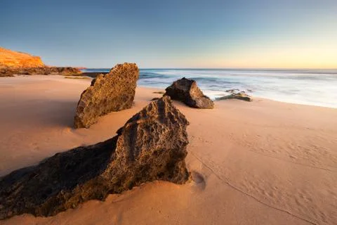 Remote beach rock formations and coastline during beautiful warm, golden sunset Stock Photos