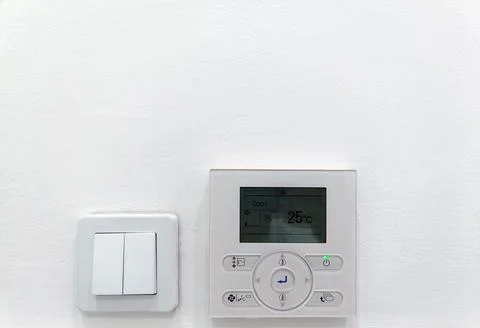 Remote central ac and light switch on white wall Stock Photos