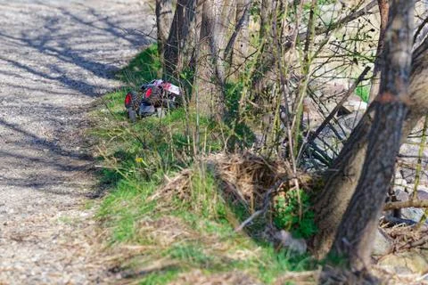 Remote control car stuck in bushes beside a gravel path in natural outdoor .. Stock Photos