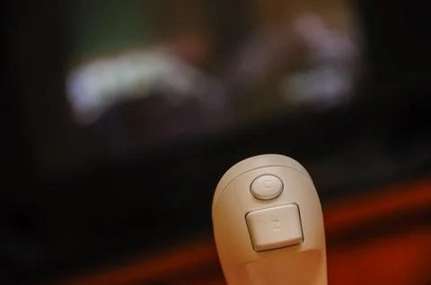 Remote control close-up with blurry TV screen in background Stock Photos
