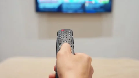 Remote control in hand switching tv channel at home Stock Footage 333265599