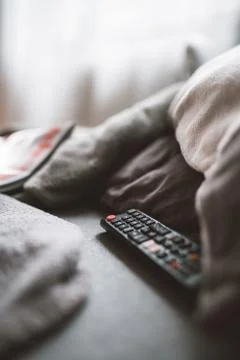 A remote control lying on a sofa between pillows Stock Photos