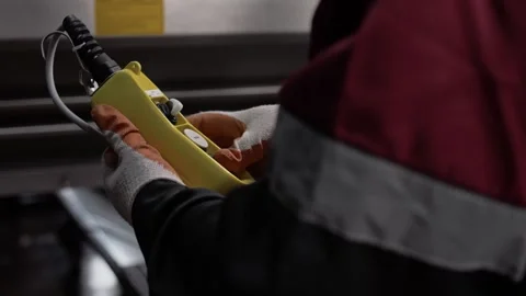 Remote control from a machine in the hands of a uniformed factory worker. Stock Footage 268750245