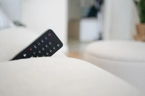 Remote control placed on the couch in a living room Stock Photos