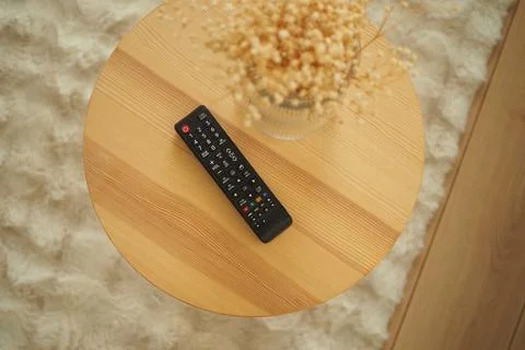 Remote control sits on a wooden table with some decoration Stock Photos