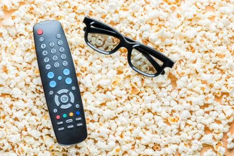 Remote control from TV and 3D glasses lie on popcorn top view Stock Photos