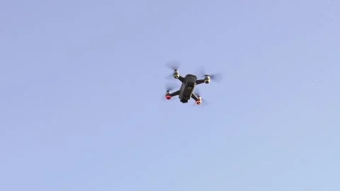 Remote controlled drone with camera flying against blue clear sky Stock Footage 133260974