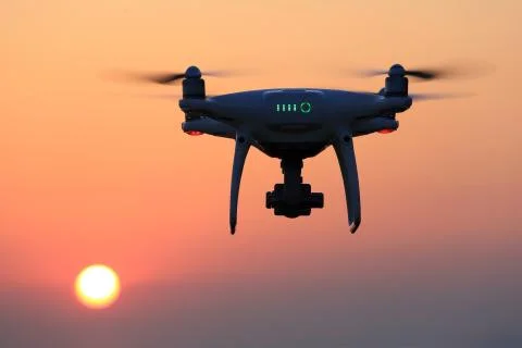 Remote controlled drone flying in air and sunset sky Stock Photos