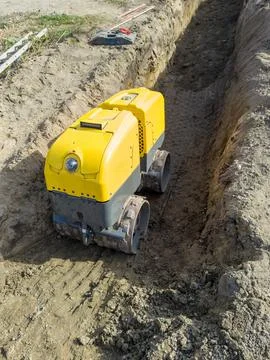 Remote controlled trench roller working on soil compaction Foto stock