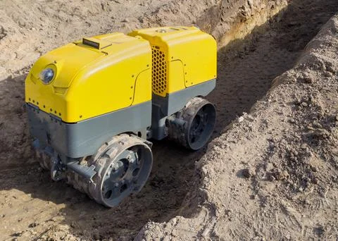 Remote controlled yellow trench compactor at construction site Foto stock