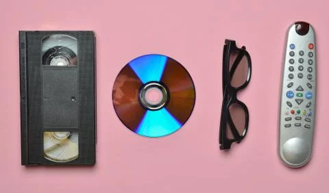 Remote controller, 3d glasses, CD, video cassette on a pink pastel background Stock Photos