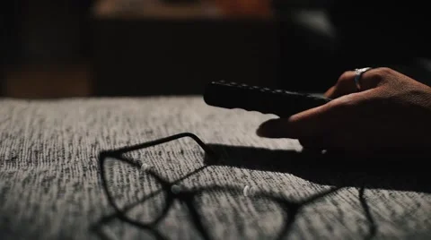 Remote controller. At the half light woman changing the channel. Tracking shot. Stock Footage 68016443