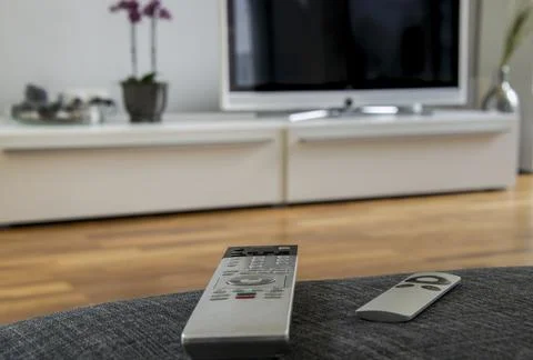 A remote controller is lying on the grey sofa with the home theater in the Stock Photos