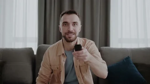 Remote controller in male hands, happy young man switching channels on smart tv Stock Footage 155077971