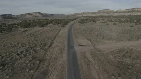 Remote desert road in a large field with mountains behind Stock-Footage 161445546