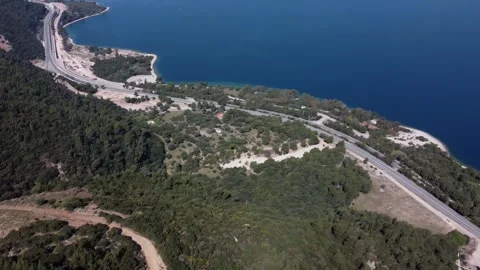 Remote dirt road crossing wild hillside toward distant coastal highway Stock Footage 344094238