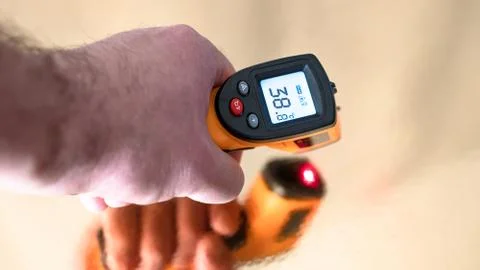 Remote electronic thermometer in hand with high temperature on the screen. Stock Photos