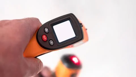 Remote electronic thermometer in hand with white screen. Stock Photos