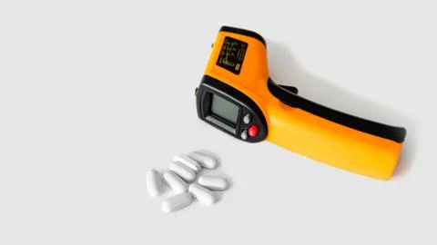Remote electronic thermometer on a white background next to pills. Stock-Fotos