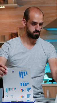 Remote employee checking graphics from clipboard using laptop Stock Photos