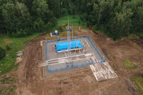 Remote gas facility in forest clearing with fenced perimeter and equipment Stock Photos