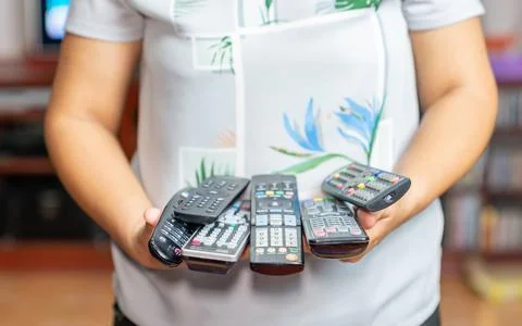 Remote on her hands for control many device in the livingroom. Stock Photos