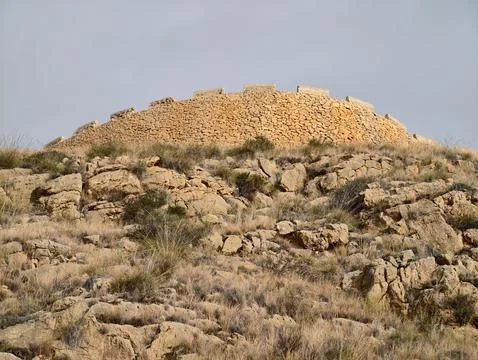 Remote hillside features aged stone marker surrounded by sparse vegetation .. Stockfoto's