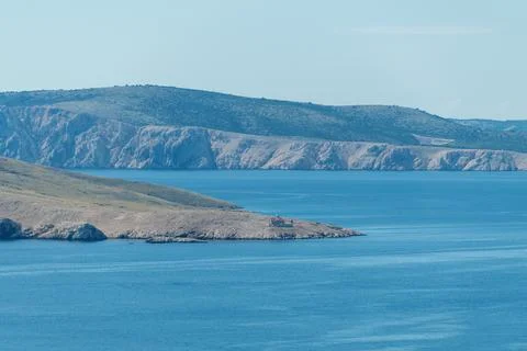 Remote island with rugged cliffs and tranquil blue waters in serene coastal.. Stock Photos