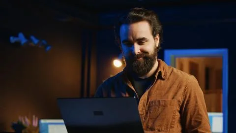 Remote IT support worker standing in home office, programming on laptop 库存照片