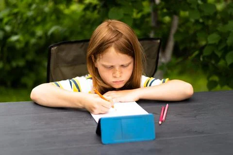 Remote learning child at a table in the garden Stock Photos