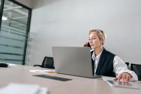Remote low-angle view of gray-haired senior adult businesswoman talking on Stock Photos