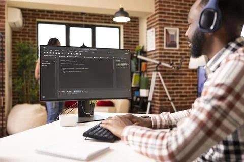 Remote male programmer sits at desk with headphones 写真素材