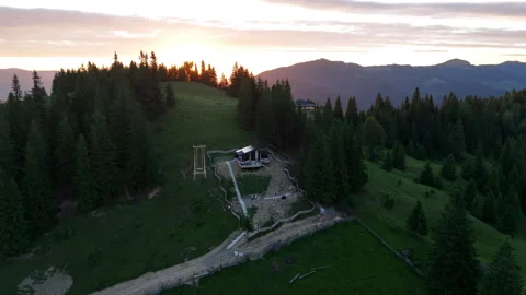 Remote mountain cabin surrounded by forest at sunrise. Aerial view of a small Stock Footage 315510931