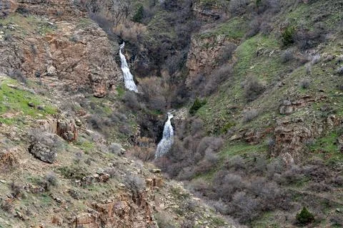 Remote mountain gorge with double waterfall and rocky terrain. 库存照片