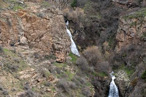 Remote mountain gorge with double waterfall and rocky terrain. Fotos de archivo